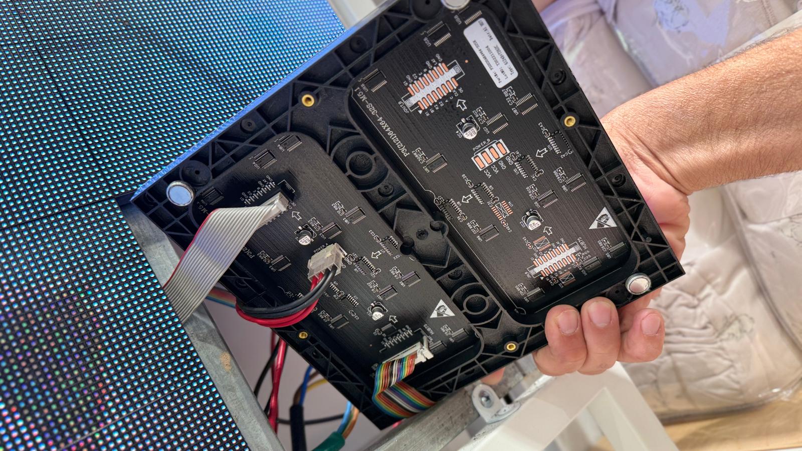 גב של מודול LED — כרטיס קליטה, מחברי חשמל וכבל נתונים, מול פאנל LED דולק